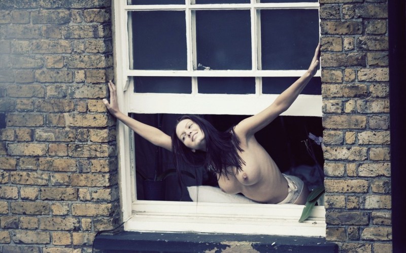 The girl undresses in the window