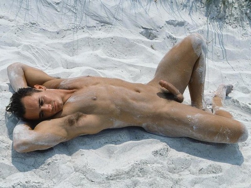 A naked guy lies on the beach